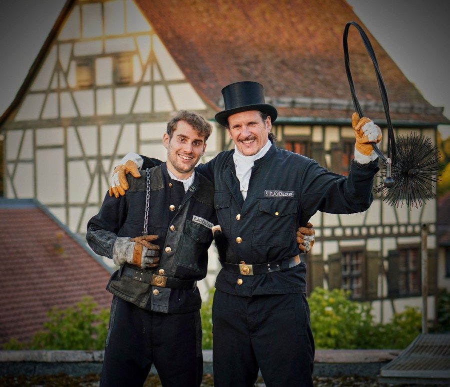 Zwei Schornsteinfeger vor einem Fachwerkhaus